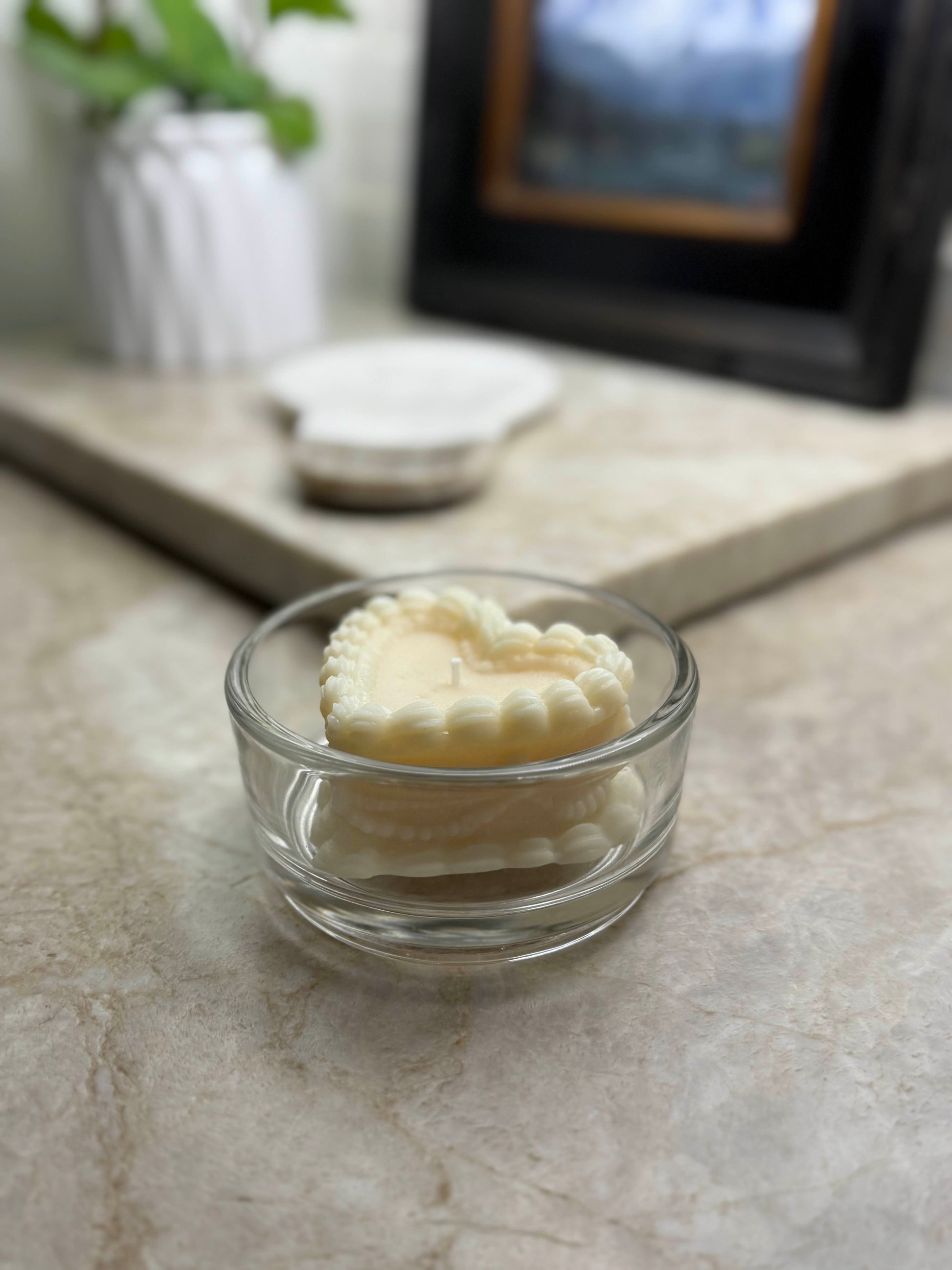 Bad Vibes vintage coquette cake candle heart shaped scalloped ivory candle in clear glass dish on marble countertop
