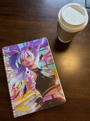 Bad Vibes holographic spiral notebook with colorful anime cyberpunk girl cover and pink coil beside coffee cup